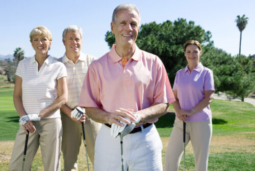 Two,Mature,Couples,Standing,On,Golf,Course,,Playing,Golf,,Smiling,